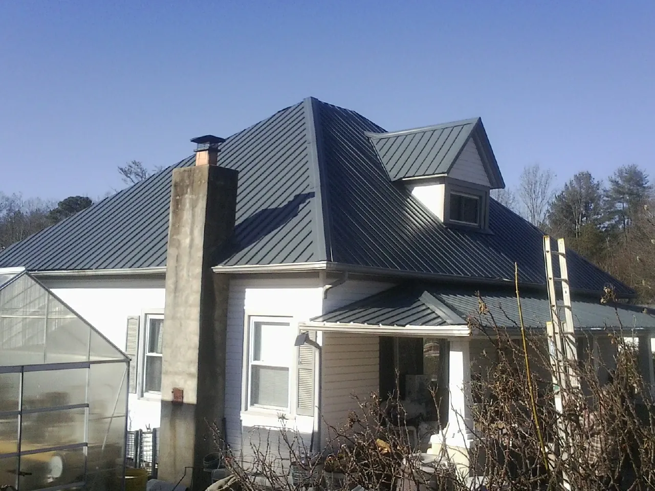 Dark blue standing seam metal roof on a white farmhouse with dormer — Slate & Tile Roof Repair by Roofing Brothers in Vermontville