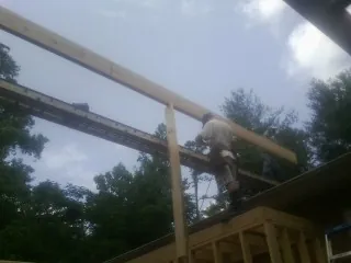 Carpenter setting a ridge beam over a new addition frame — Ice Dam Removal by Roofing Brothers in Vermontville