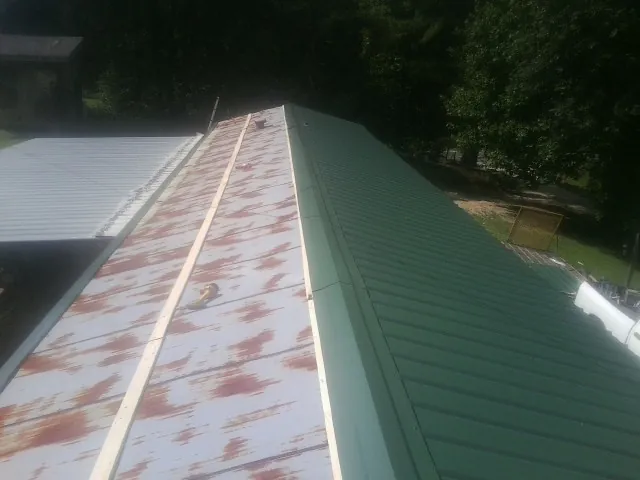 Old rusted panels beside newly installed green metal roofing — Wind Damage Roof Repair by Roofing Brothers in Vermontville