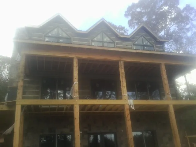 Dormers and porch framing on a large log home under construction — Roof Coating work by our crew in Vermontville