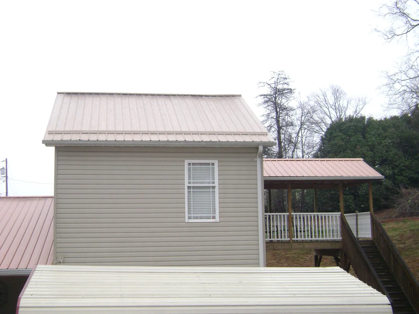 Tan metal roofs on a two story addition and attached porch, from a Roof Replacement job in Vermontville