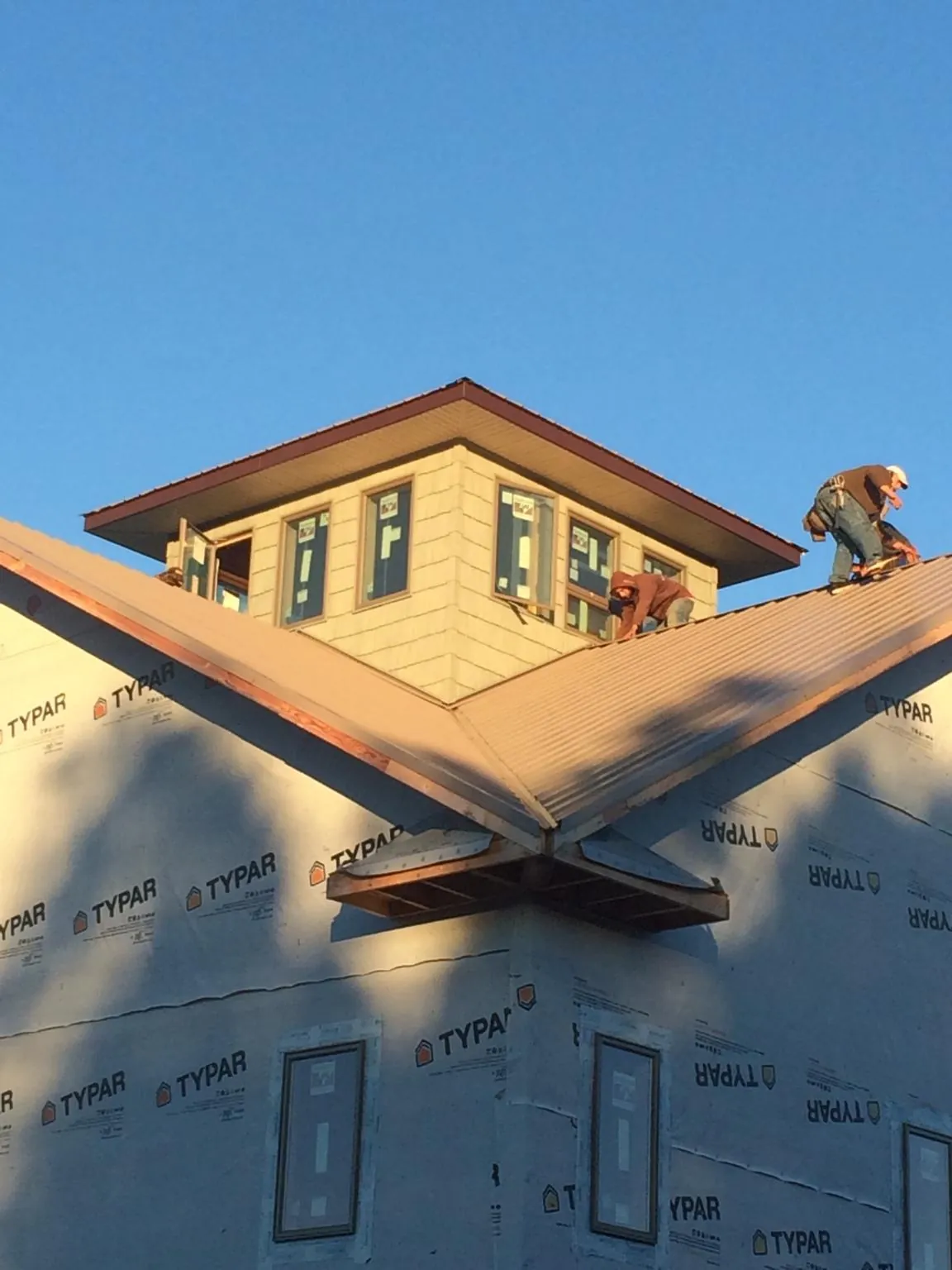 Roofers working around a rooftop cupola on a new metal roof at sunset — Roof Waterproofing in Vermontville by Roofing Brothers